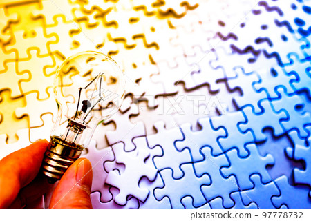 A hand holding a light bulb that sparks an idea Background texture of a disjointed jigsaw puzzle Strategy Light and dark image rainbow color 97778732