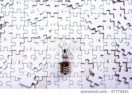 Sparking ideas Background texture of scattered jigsaw puzzles and light bulbs Strategies clearly 97778891