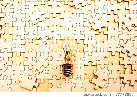 Sparking ideas Background texture of scattered jigsaw puzzles and light bulbs Strategies Clear gold 97778893