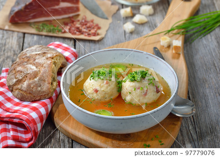 Delicious South Tyrolean bacon dumplings soup with hot beef broth and chives 97779076