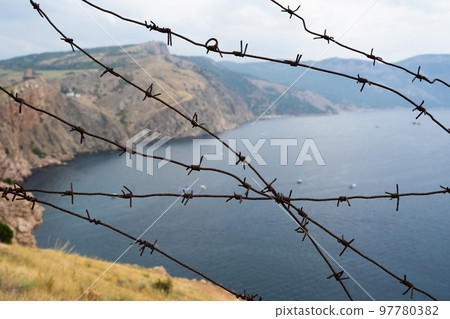military border of barbed wire at sea in the mountains military border of barbed wire at sea in the mountains 97780382