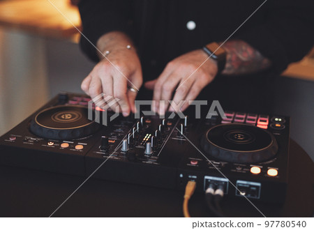 a DJ plays music on a controller at a party. a DJ plays music on a controller at a party. 97780540