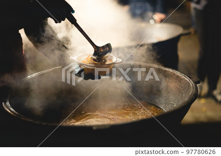 the cook fills a bowl with hot street food the cook fills a bowl with hot street food 97780626