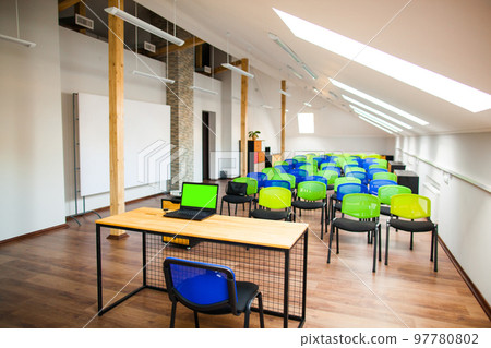 modern lecture room with with colored chairs and interesting design, laptop on the table, green screen modern lecture room with with colored chairs and interesting design, laptop on the table, green screen 97780802