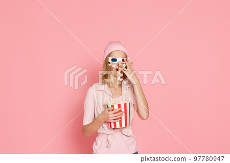 terrified girl watching horror movie , holding bucket of popcorn 97780947