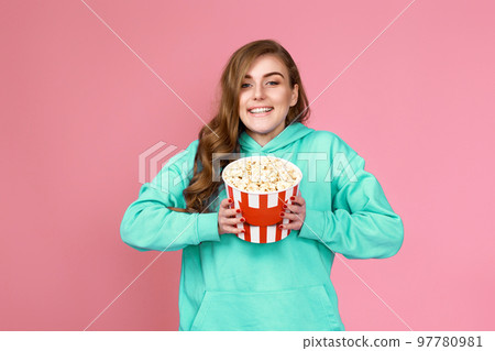 woman in sweatshirt watching movie film, eating popcorn woman in sweatshirt watching movie film, eating popcorn 97780981
