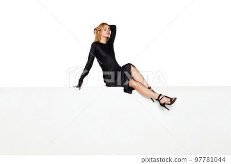 blonde woman with long legs sitting on white bench. 97781044