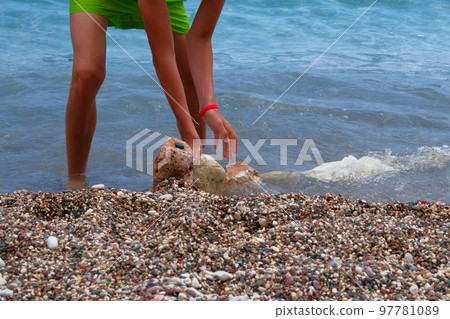 Active children summer vacation at sea. Boy in green shorts is relaxing on sea coast. Sunny summer day. Active children summer vacation at sea. Boy in green shorts is relaxing on sea coast. Sunny summer day. 97781089