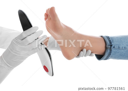 Orthopedist fitting insole on patient's foot against white background, closeup 97781561