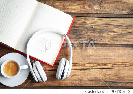 Book, coffee and headphones on wooden table, flat lay. Space for text 97781600