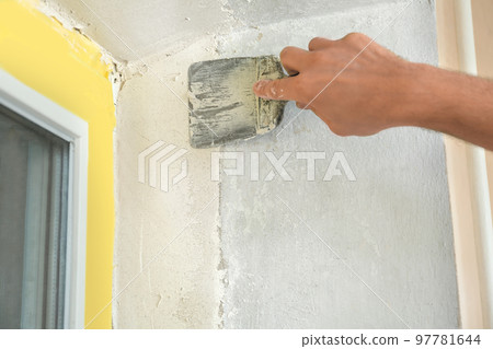 Man plastering window area with putty knife indoors, closeup. Interior repair Man plastering window area with putty knife indoors, closeup. Interior repair 97781644