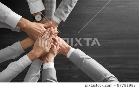 People holding hands together over grey wooden background, top view. Unity concept People holding hands together over grey wooden background, top view. Unity concept 97781982