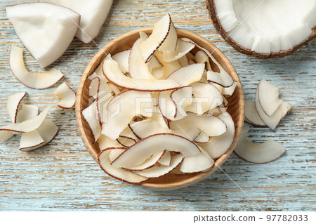 Tasty coconut chips on light blue wooden table, flat lay Tasty coconut chips on light blue wooden table, flat lay 97782033