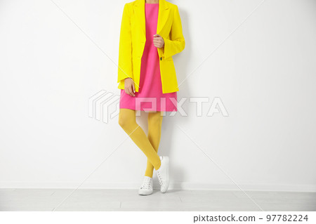 Woman wearing yellow tights near white wall, closeup 97782224