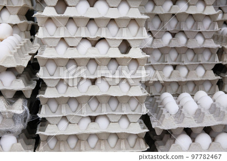 Chicken white eggs in cardboard boxes stacked in rows in store. Eggs in package. 97782467