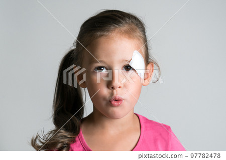 Cute sad disappointed dark haired little kid girl with injury, scratch and patch plaster on face, making lips in tube Cute sad disappointed dark haired little kid girl with injury, scratch and patch plaster on face, making lips in tube 97782478