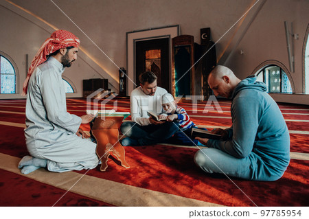 A group of Muslims reading the holy book of the Quran in a modern mosque during the Muslim holiday of Ramadan 97785954