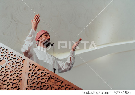 Muslims arabic Imam has a speech on friday afternoon prayer in mosque. Muslims have gathered for the friday afternoon prayer in mosque and are listening to the speech of imam 97785983