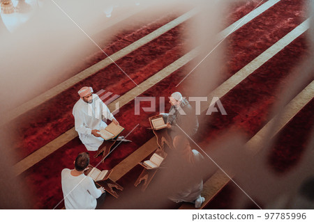 A group of Muslims reading the holy book of the Quran in a modern mosque during the Muslim holiday of Ramadan A group of Muslims reading the holy book of the Quran in a modern mosque during the Muslim holiday of Ramadan 97785996