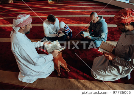 A group of Muslims reading the holy book of the Quran in a modern mosque during the Muslim holiday of Ramadan 97786006