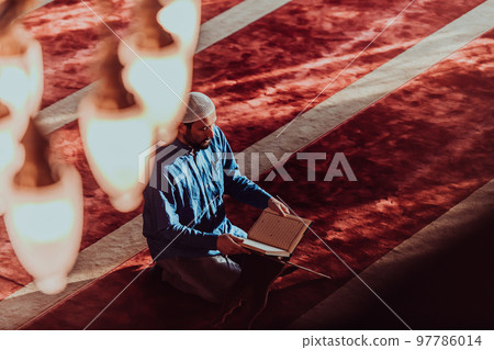 A Muslim reads the holy Islamic book Quraqn in a modern grand mosque during the Muslim holy month of Ranazan 97786014