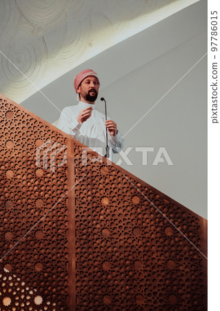 Muslims arabic Imam has a speech on friday afternoon prayer in mosque. Muslims have gathered for the friday afternoon prayer in mosque and are listening to the speech of imam Muslims arabic Imam has a speech on friday afternoon prayer in mosque. Muslims have gathered for the friday afternoon prayer in mosque and are listening to the speech of imam 97786015