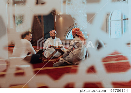 A group of Muslims reading the holy book of the Quran in a modern mosque during the Muslim holiday of Ramadan 97786134
