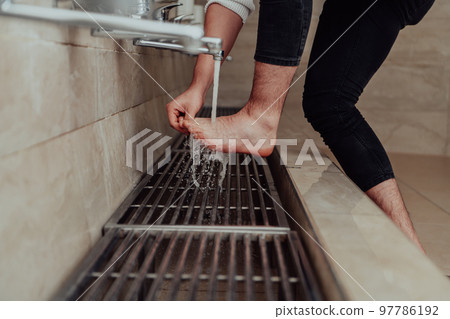 A Muslim performing ablution. Ritual religious cleansing of Muslims before performing prayer. The process of cleansing the body before prayer 97786192
