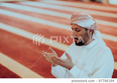 Muslim Arabic man praying. Religious muslim man praying inside the mosque during ramadan Muslim Arabic man praying. Religious muslim man praying inside the mosque during ramadan 97786194
