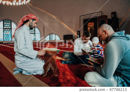 A group of Muslims reading the holy book of the Quran in a modern mosque during the Muslim holiday of Ramadan 97786213