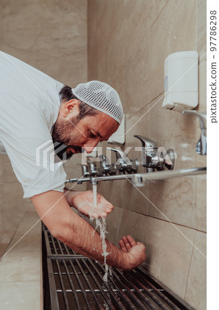 A Muslim performing ablution. Ritual religious cleansing of Muslims before performing prayer. The process of cleansing the body before prayer A Muslim performing ablution. Ritual religious cleansing of Muslims before performing prayer. The process of cleansing the body before prayer 97786298