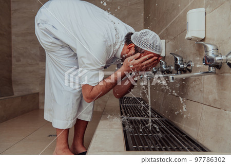 A Muslim performing ablution. Ritual religious cleansing of Muslims before performing prayer. The process of cleansing the body before prayer A Muslim performing ablution. Ritual religious cleansing of Muslims before performing prayer. The process of cleansing the body before prayer 97786302