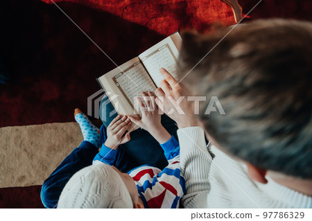 Muslim prayer father and son in mosque praying and reading holly book Quran together islamic education concept 97786329
