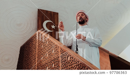 Muslims arabic Imam has a speech on friday afternoon prayer in mosque. Muslims have gathered for the friday afternoon prayer in mosque and are listening to the speech of imam Muslims arabic Imam has a speech on friday afternoon prayer in mosque. Muslims have gathered for the friday afternoon prayer in mosque and are listening to the speech of imam 97786363