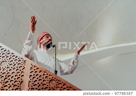 Muslims arabic Imam has a speech on friday afternoon prayer in mosque. Muslims have gathered for the friday afternoon prayer in mosque and are listening to the speech of imam Muslims arabic Imam has a speech on friday afternoon prayer in mosque. Muslims have gathered for the friday afternoon prayer in mosque and are listening to the speech of imam 97786387