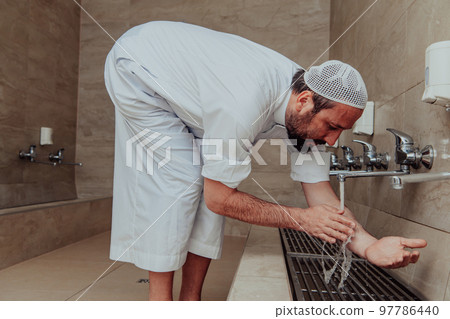 A Muslim performing ablution. Ritual religious cleansing of Muslims before performing prayer. The process of cleansing the body before prayer A Muslim performing ablution. Ritual religious cleansing of Muslims before performing prayer. The process of cleansing the body before prayer 97786440