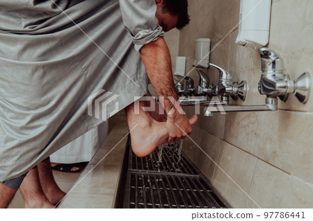 A Muslim performing ablution. Ritual religious cleansing of Muslims before performing prayer. The process of cleansing the body before prayer A Muslim performing ablution. Ritual religious cleansing of Muslims before performing prayer. The process of cleansing the body before prayer 97786441