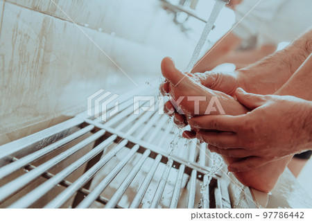 A Muslim performing ablution. Ritual religious cleansing of Muslims before performing prayer. The process of cleansing the body before prayer A Muslim performing ablution. Ritual religious cleansing of Muslims before performing prayer. The process of cleansing the body before prayer 97786442