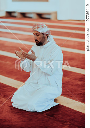 Muslim Arabic man praying. Religious muslim man praying inside the mosque during ramadan Muslim Arabic man praying. Religious muslim man praying inside the mosque during ramadan 97786449