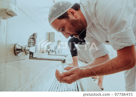 A Muslim performing ablution. Ritual religious cleansing of Muslims before performing prayer. The process of cleansing the body before prayer A Muslim performing ablution. Ritual religious cleansing of Muslims before performing prayer. The process of cleansing the body before prayer 97786455
