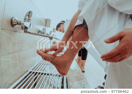 A Muslim performing ablution. Ritual religious cleansing of Muslims before performing prayer. The process of cleansing the body before prayer A Muslim performing ablution. Ritual religious cleansing of Muslims before performing prayer. The process of cleansing the body before prayer 97786462
