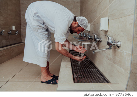 A Muslim performing ablution. Ritual religious cleansing of Muslims before performing prayer. The process of cleansing the body before prayer A Muslim performing ablution. Ritual religious cleansing of Muslims before performing prayer. The process of cleansing the body before prayer 97786463