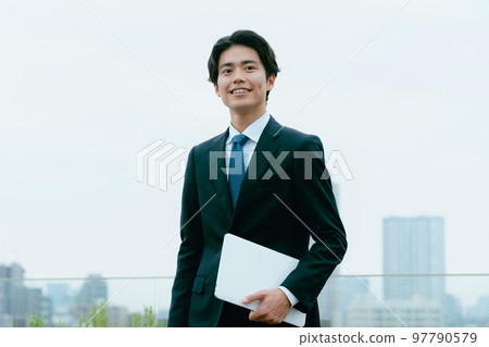 Businessman standing with a computer on the roof Businessman standing with a computer on the roof 97790579