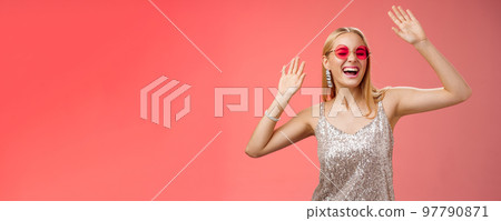 Happy amused carefree blond woman go wild dance-floor dancing having fun yelling yeah closed eyes waving hands moving rhythm music joyfully party in silver stylish dress sunglasses, red background Happy amused carefree blond woman go wild dance-floor dancing having fun yelling yeah closed eyes waving hands moving rhythm music joyfully party in silver stylish dress sunglasses, red background 97790871