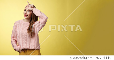 Attractive triumphing arrogant and confident cute glamourous woman in knitted sweater, headband showing l letter on forehead, loser sign and laughing over lost team, mocking having fun 97791110
