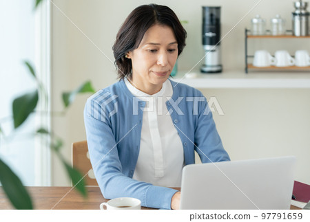 A middle-aged woman doing research on a computer 97791659