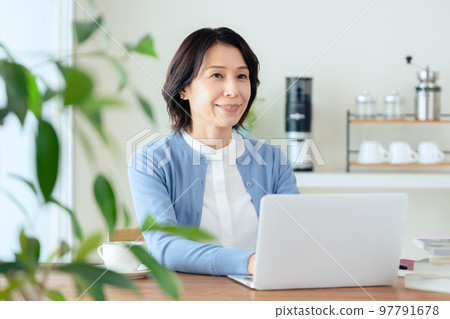 A middle-aged woman doing research on a computer 97791678