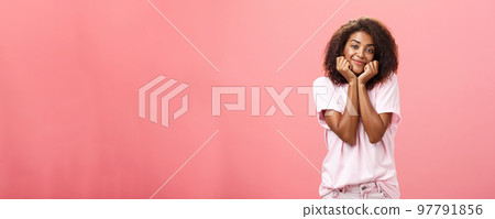Dreamy nostalgic african american girlfriend with curly hairstyle sighing leaning head on palms and smiling gently as if imaging or gazing at boyfriend with affection having feelings for friend 97791856