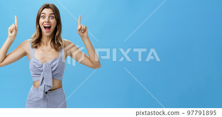 Thrilled and amused happy charming caucasian woman with tattoo and gapped tooth in trendy outfit smiling broadly from amazement and happiness raising hands pointing up with index fingers excited 97791895