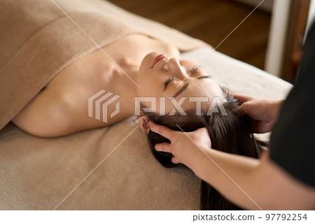 Woman receiving head massage at beauty salon 97792254